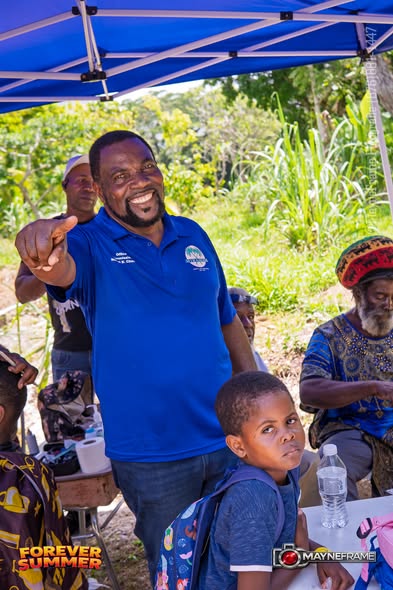 A smiling volunteer in a blue New Hope shirt pointing toward the camera
